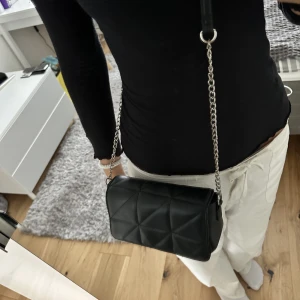 Svart axelbands väska  - Svart axelbands väska i syntetläder med silver kedja.🤍