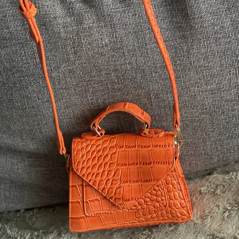 Jätte fin liten orangeväska, den har ett långt band som man kan justera. Väskor.