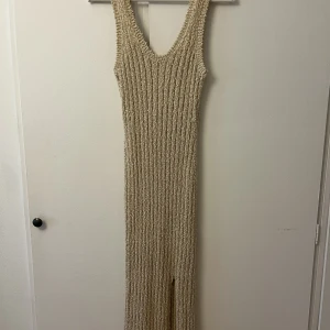 Midiklänning i guld - Jättefin klänning från &otherstories i guld med lite vitt med en slits längst ner. Den köptes för flera år sedan med nypris ca 900kr och är nu för liten. Frakt ingår ej i priset
