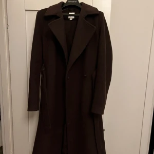 Kappa  - En brun kappa från HM med ett skärp i midjan, väldigt gott skick då den endast är använd ett fåtal gånger.