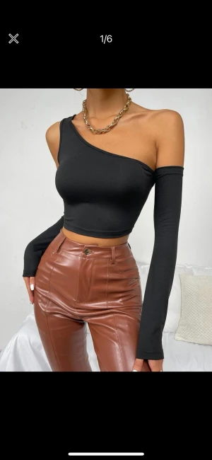 Svart topp med one-shoulder  - Den här toppen har ett one-shoulder-look, en croppad längd och ett stretchigt material. Den här toppen kommer i svart. Oanvänd!