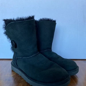 Äkta Uggs i toppen skick! - Super fina, äkta uggs näst intill oanvända! Är en ganska klassisk model i svart med en knapp på yttersidan. Otroligt sköna och varma, är köpta i USA för några år sedan men har mest stått i en garderob sedan dess, därav är dem i dunder skick!