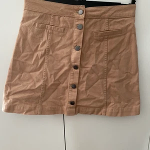 Beigekjol med knappar, strl 38 - Aldrig använd med lappen kvar. Strl 38. Obs köparen står för frakt