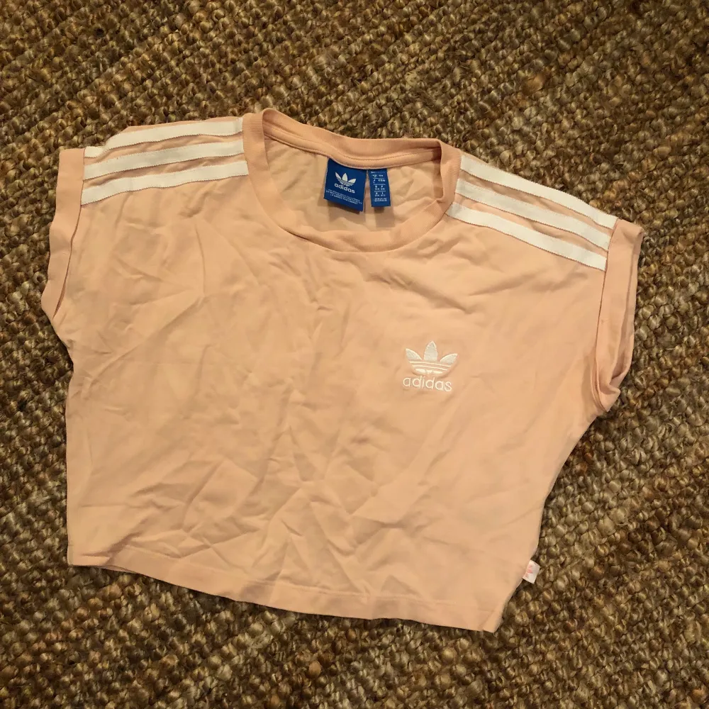 Ljusrosa t-shirt (crop top) från adidas storlek XS/34. Fint skick! Hämtas i Årsta eller skickas mot porto.. T-paidat.