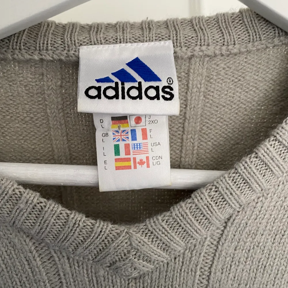 En grå stickad adidas tröja som är köpt secondhand  i Köpenhamn. Den är till viss del lite stickig men funkar jättebra om man har ett linne under eller liknande. Är i storlek L men blir inte jätte oversized på mig som är M/L. Stickat.