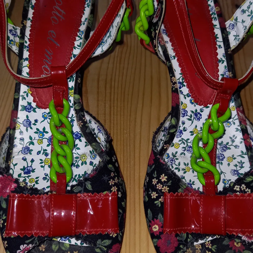 Blommig svartbotten/röda rosor/grön kedja Klackhöjd:8,5 cm Tyg på ytter sida/lack Skinn som innerfoder och sula Str:38 Sparsamt använd sko. Skor.