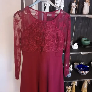 Klänning  - En vinröd klänning i storlek 40 med blommiga detaljer dragkedja i ryggen använd få tal gånger den är från NLY ONE 