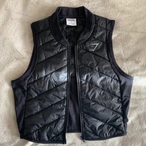 Gymshark väst - (Andra bilden lånad) säljer denna sprillans nya väst i storlek M, dem är väldigt små i storleken så denna sitter mer som en S. Sitter som på modellen på bilden! Köptes för 499:-. Köparen står för frakten!