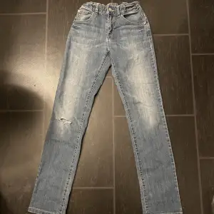 Ett par blåa bootcut liknade jeans, storlek xs/s, man kan justera i midjan med resår band. Sitter precis vid naveln, är tajta på låren och lite utspläppta på vaderna, har ett hål på höger knä