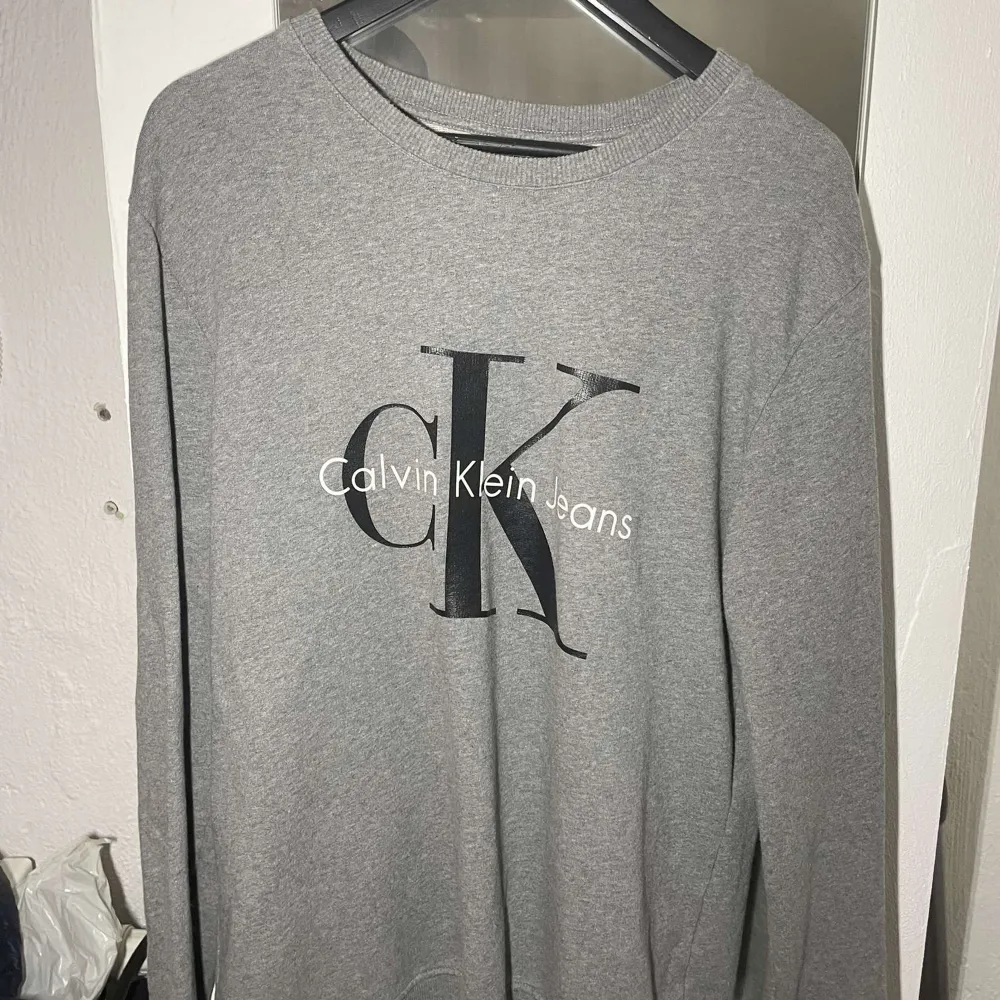 Jättefin grå Calvin Klein tröja med tryck storlek L. Inte mycket använd, väldigt fint skick. Nypris ca 1000kr. Tröjor & Koftor.