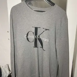 Jättefin grå Calvin Klein tröja med tryck storlek L. Inte mycket använd, väldigt fint skick. Nypris ca 1000kr