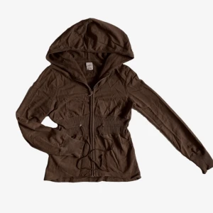 Hoodie  - Brun hoodie, lite kortare modell och resår i midjan så man ser figuren. Gott skick! Stl M men passar även bra på mig som har S! Färgen ser lite flammig ut på bild 2 men det är bara på bilden och inte i verkligheten 