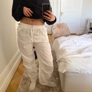 Vita fallskärmsbyxor - Säljer dessa vita fallskärmsbyxor från bershka. Har endast använt dom en gång och är därför så gott som nya, passar mig bra som är 174cm. Man kan även justera dom i midjan och längst ner💗