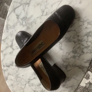 Svarta pumps i präglat läder - Präglat läder som ser flätat ut. Skinfodrade i tån. Kraftig klack. Vintagekänsa.