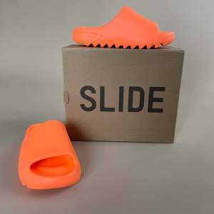 Brand New, Never Worn. Make a bold statement with these super comfy slides Color: Enflamed Orange US/UK Size 5  It’s recommended by retailers to go a full size up from your usual size.  Made of Resin Comes with Original packaging