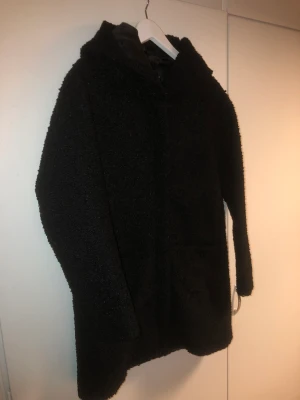 Svart kappa - Svart kappa från BikBok i storlek S. Pilématerial och luva. I bra skick. Passar till höst/vår.