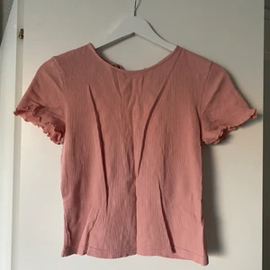 Topp från H&M Strl M - Gammelrosa topp från H&M i Strl M. Toppen har volangdetaljer i ärmarna samt broderi och snörning på baksidan. 