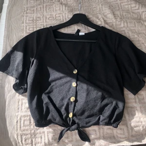 Svart topp från H&M storlek xs - Så fin svart topp från H&M i storleken xs. Knappar och en lite knytning längst ned på toppen✨