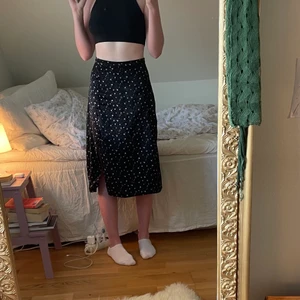 Blommig kjol - Blommig kjol med slit och dekorativa knappar. Stl s 