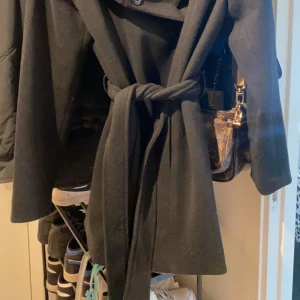 Svart kappa  - Svart kappa med huva, använd endast två gånger då det inte riktigt är min stil, köpte för 600kr säljer för 299+frakt 