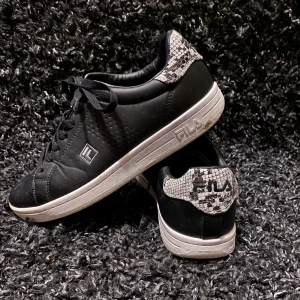 Fila sneakers  - Svarta fila sneakers med snakeskin print på hälen. Använda fåtal gånger. - strl 39