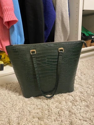 Grön ”skinn” väska - Grön väska, minns ej vart jag köpt den då jag klippt av lappen som man ser på bild. Använd fåtal gånger 