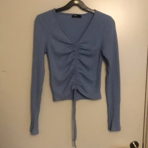 Topp - Ljusblå topp med snörning i mitten.