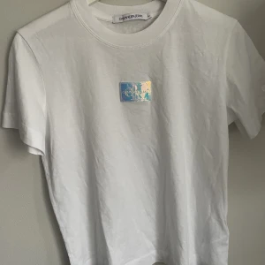 Calvin Klein T-shirt - Skitcool Calvin Klein t-shirt med färgskiftande logga🌟 Aldrig använd. Det är M men passar som ett S skulle jag säga. 