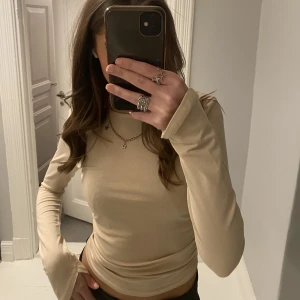 Beige topp  - Säljer denna jätte fina beiga tröja från Nelly, använd endast en gång så är därför i ett väldigt bra skick 