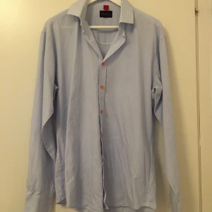 Herrskjorta, Dahlin by Eberstål - Fin skjorta med små ränder i vitt och ljusblått, färgglada knappar i orange. Storlek M