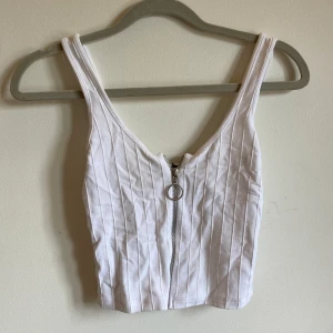 Vitt linne med dragkedja - Vitt fest linne som jag köpte för fyra år sen i Hastings, England. Har däremot inte använt plagget de senaste två åren då det varit för litet. Tröjan har en dragkedja som man kan dra upp och ner. Storlek XS från Bershka.