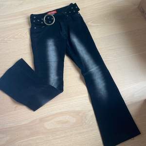 Lågmidjade jeans i svart Manchester tyg med tillhörande bälte. Stretchigt tyg. Pyttelitet hål vid en av öglorna till bältet men det syns inte när man har de på. Storlek 36