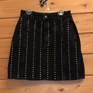 Rockstjärna denim kjol - Känn dig som en riktig rockstjärna med den här denimkjolen med reflekterande paljetter! Materialet är 100% bomull och kjolen är 110% cool. Färgen är svartgrå med en tvättad effekt och kjolen har aldrig använts.