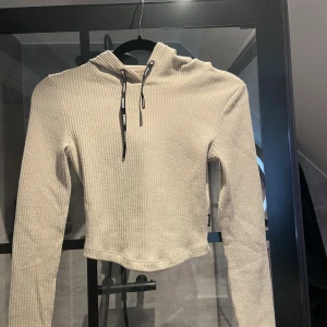 Ribbad tröja  - Beige ribbad tröja ifrån stronger. Croppad tight långärmad med luva och band. Tröja är i strl Xs och i bra skick. Bud om fler är intresserade❤️