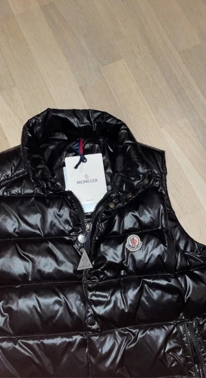 Moncler väst  -  Svart moncler väst 7/10 i skick, inge hål eller liknande defekter men har nu blivit för liten för mig! Tags och påse följer med! Använd väst där av priset 