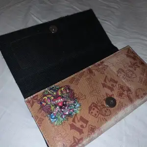 Ed hardy plånbok Väldigt blekt som ni kan se på färgskillnaden men enligt mig blir den bara snyggare. Ca 20cm X 6cm Köpare betalar frakt