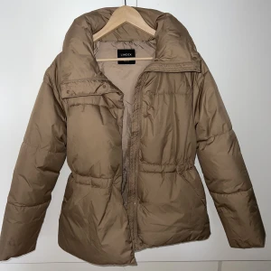 Beige vinterjacka  - Super snygg beige vinterjacka från Lindex i storlek XS.  Dragsko i midjan, ger en fin form i midjan och  går att reglera hur man själv önskar! 