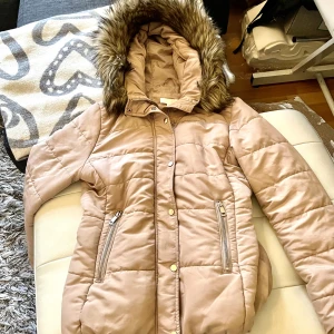 Vinterjacka beige 38 guldknappar  - Varm fodrad snygg vinterjacka beige 38. Snygga detaljer med band i midjan päls och guldknappar. 