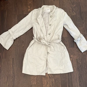 Kappa - Kappa/trenchcoat säljs för 150kr, nypris 500kr. Använd under en höst, säljer pga förkort i armarna. Fraktkostnad tillkommer. Färgen är beige inte grå!