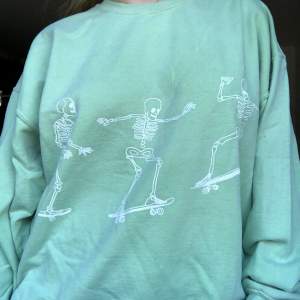Mintgrön hoodie från Urban Outfitters med skelett som skatar på. Finns lite fläckar på ärmarna mest (se sista bilden) men ingen som stör jättemycket tycker inte jag