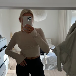 Ribbad tröja - Fin ribbad topp/tröja med öppen rygg som man knyter och slits i armen. Bra skick eftersom att den inte är använd.💗