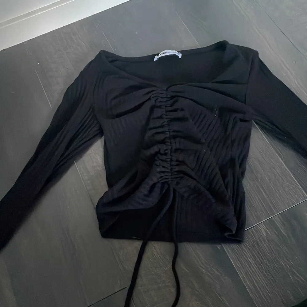 En svart tröja med 2 band som man kan fixa hur kort tröjan ska vara i storlek xxs . Tröjor & Koftor.