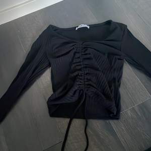En svart tröja med 2 band som man kan fixa hur kort tröjan ska vara i storlek xxs 