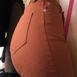 Orangea byxor - Tjockare tyg men snäll/mjuk strech, mid-rise, raka men lite smalare i midjan. Bra skick. Säljs för att det är på håret att jag får på mig dom. Min stussvidd är 100cm
