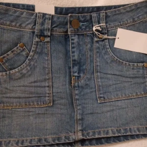.NY + oanvänd kort jeanskjol. Denim. Denimblå. Storlek: XS / 34. Märke: Crocker/JC. - Helt NY oanvänd kort denimblå jeanskjol från Crocker/JC. Har fickor fram+bak samt hällor för bälte/skärp. Stängs med dragkedja och knapp framtill. Strlk: XS/34. Lappar/tags sitter kvar sedan inköpet. Nypris i butik 399 kr. Felfri. FRAKT TILLKOMMER. BUDA.