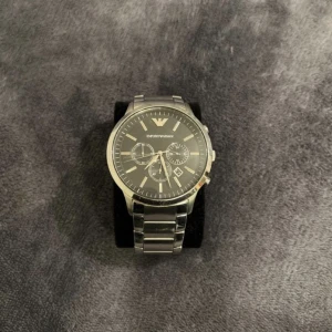 Armani Klocka - Modell: AR2460 - Nypris: Mellan 3500-4000kr. - Skick: I gott skick, inga synliga skador på urtavlan respektive länkarna.  - 46mm - Silverfärgad länk, svart urtavla.