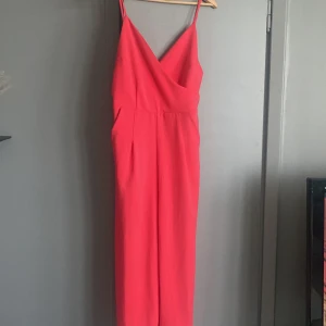 Jumpsuit - Rosa jumpsuit med kortare ben och fickor. Dragkedja bak i ryggen. Stl M från bikbok