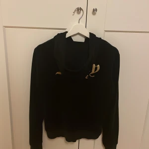 Svart Juicy Couture tröja - Svart Juicy Couture tröja med guldig text. Den är i bra skick. Storlek 14/15 år (164-170). Jag säljer den för att den inte kommer till användning. Den kostar 650 kr i ny pris.