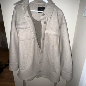Kappa med bälte  - Beige kort kappa från bikbok. Köpt förra året men endast använd fåtal ggr. Stl S. Nypris 699kr.