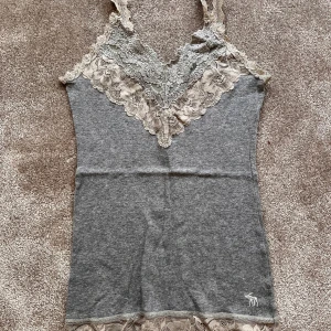 Linne med spets  - Ett grått linne med fin spets uppe och nertill från Abercrombie & Fitch. Storlek XS